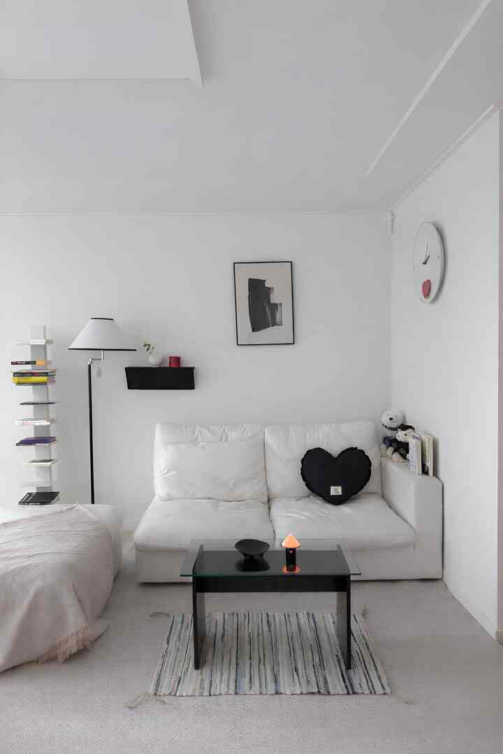 A modern, clean living room in white and black tones featuring a white sofa and simple black coffee table