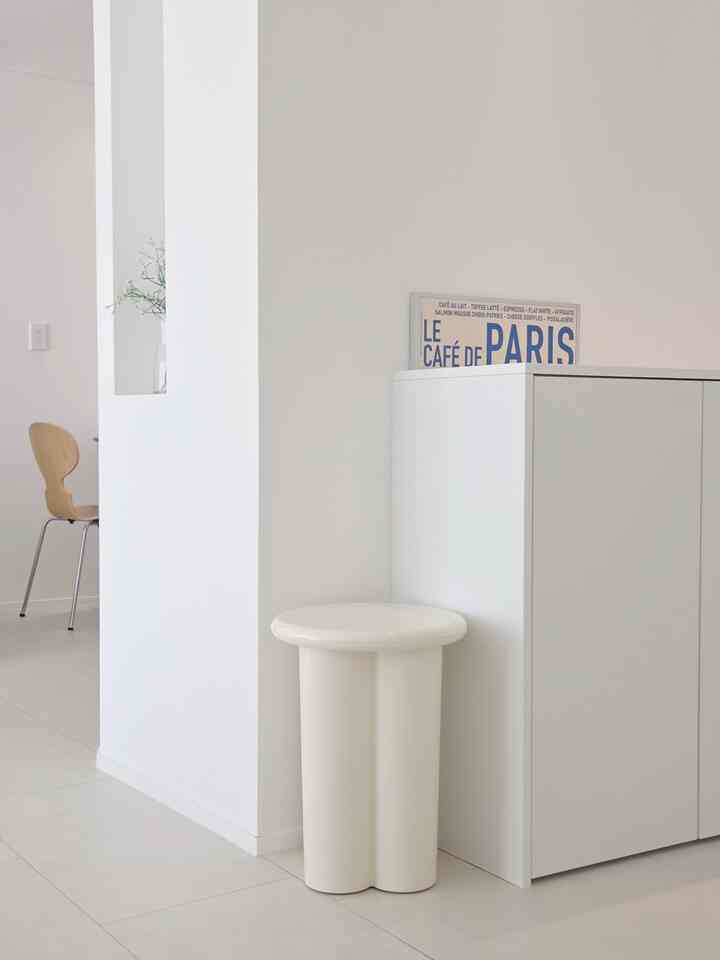 ホワイトトーンのダイニング、ナチュラルな木製ダイニングチェアとシンプルな収納が配置された雰囲気のあるインテリア