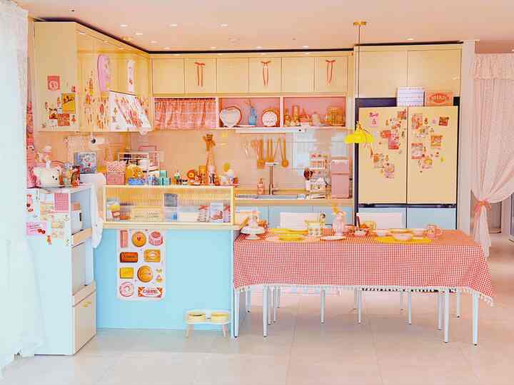 バター色とミント、ピンクのトーンが調和したラブリーなキッチン、可愛らしい小物と格子模様のテーブルクロスが配置された暖かみのある空間
