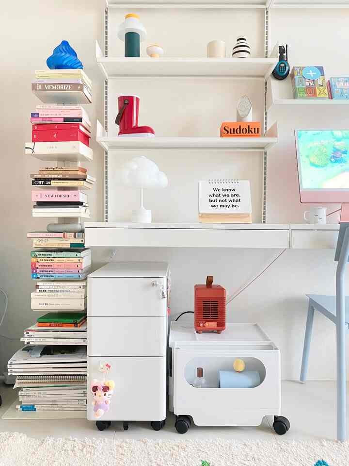 White and blue toned home office space featuring a neatly organized desk and stacked books, conveying a simple and calm atmosphere