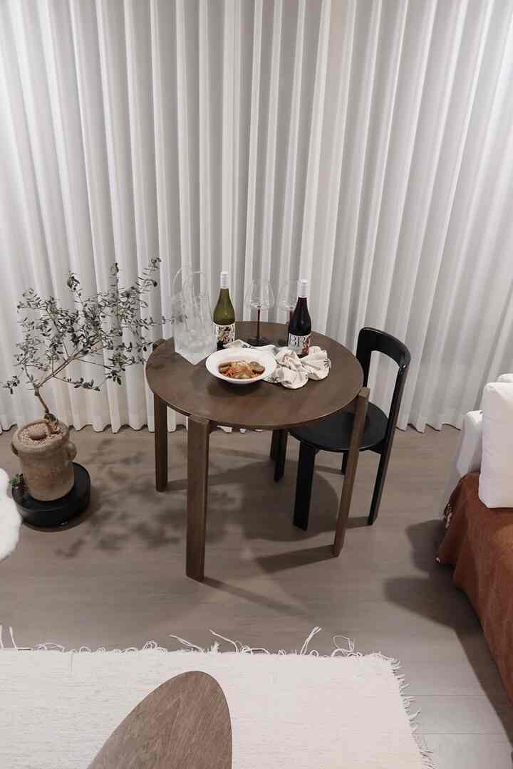 Natural modern living room with white tones featuring a brown wooden dining table and black dining chair