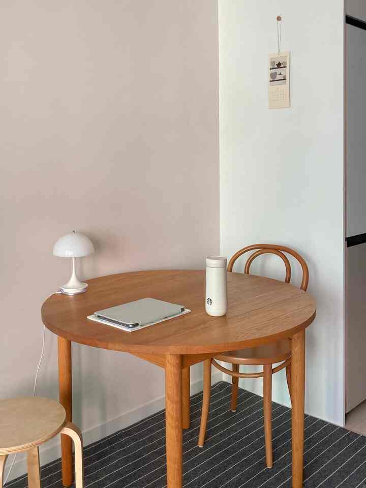 ホワイトとブラウンのトーンのダイニングスペース、木製のテーブルと椅子が配置されたミニマルな雰囲気のインテリア