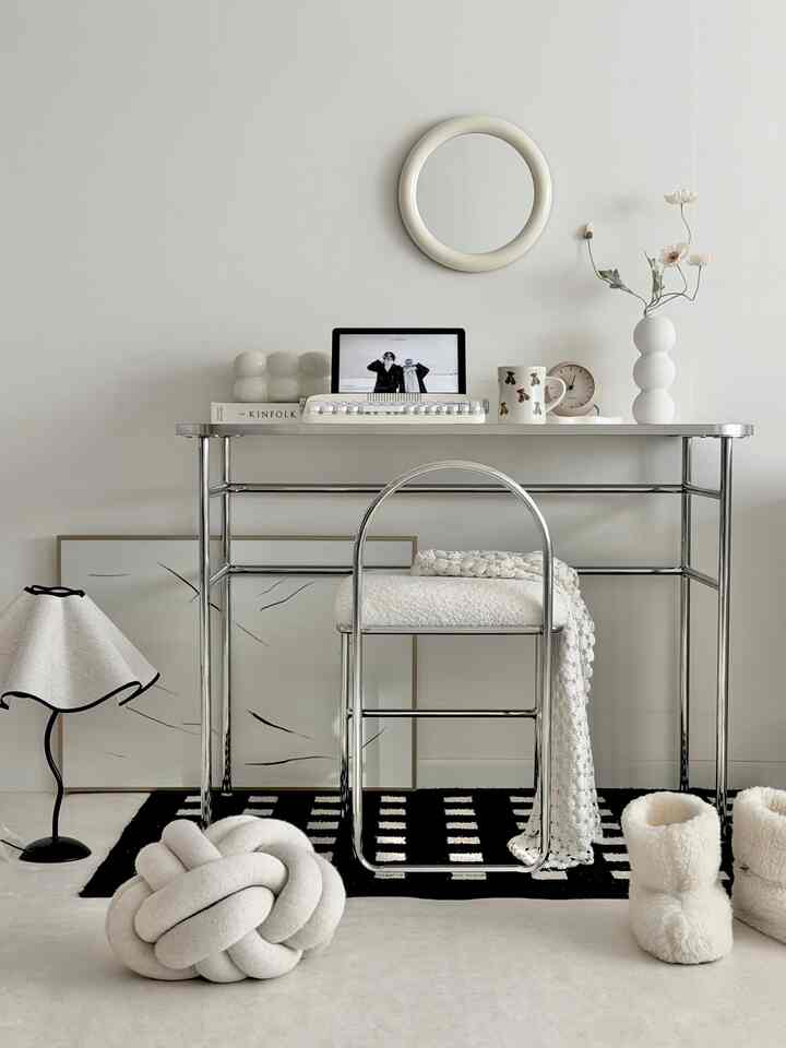 Monotone and natural color-toned home office featuring chrome desk and chair with round mirror and decor, minimalist and neat interior