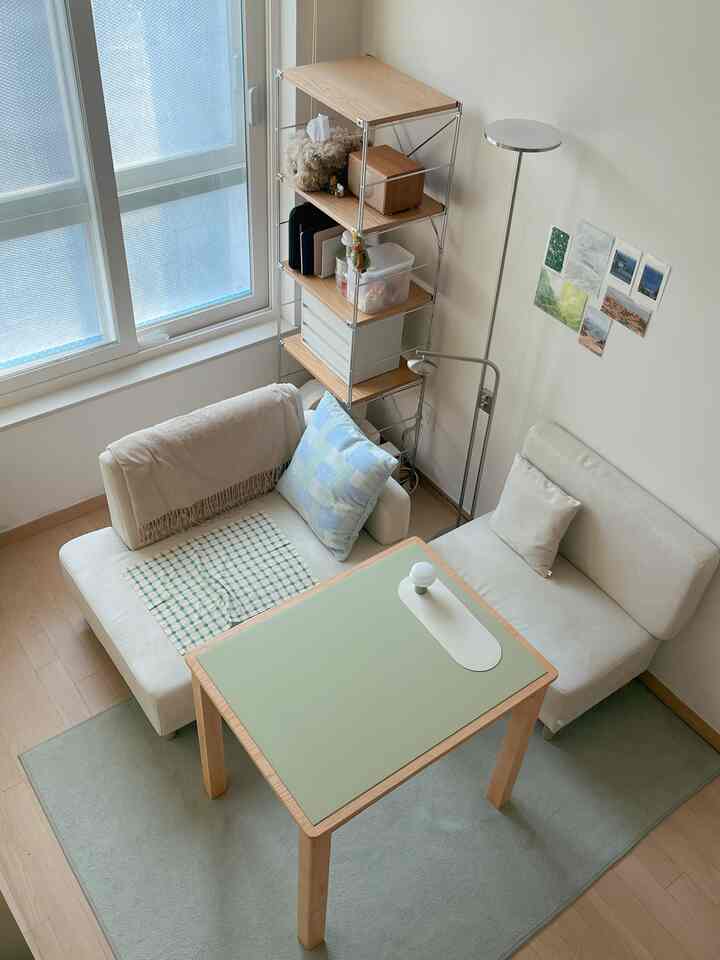 ウッドトーンとアイボリーを基調としたコンパクトなワンルームリビング、抹茶グリーンのテーブルとラグがアクセントに配置されている雰囲気のあるインテリア