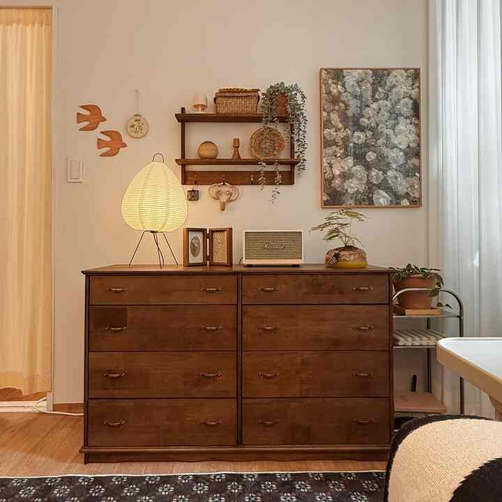 ベージュ色の壁と木目調のチェストや棚が配置された、雰囲気のあるヴィンテージ風のコンパクトな空間