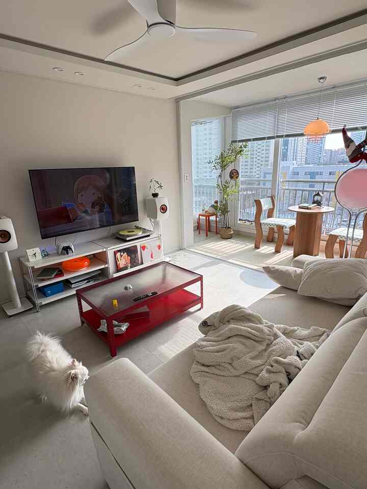 ナチュラルな色調のリビング、ベージュソファと赤いコーヒーテーブルが配置された印象的な空間