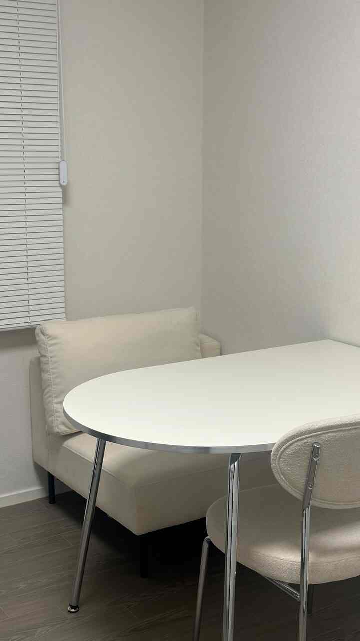 アイボリーとシルバー色調のミッドセンチュリースタイルの一人掛けソファ、テーブル、椅子が配置された清潔感のある書斎空間