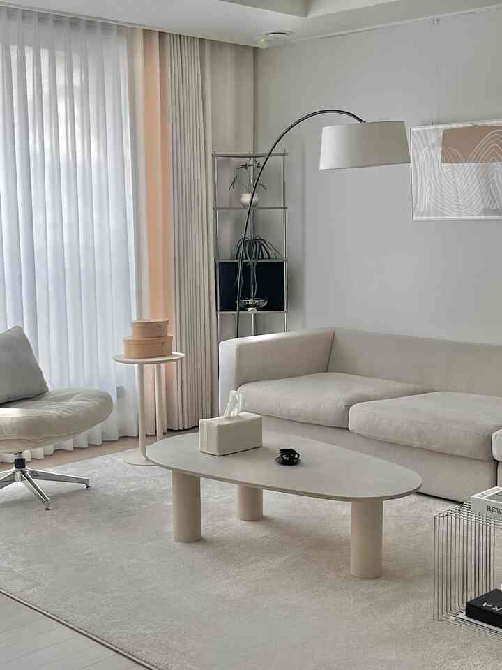 ライトベージュとウッドトーンのシンプルモダンなリビング、ホワイトソファと回転チェア、ミニマルなコーヒーテーブルが配置された雰囲気のあるインテリア