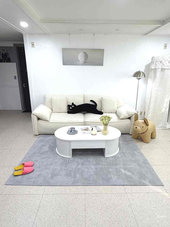 白とシルバーの色調が特徴のリビング、シンプルモダンなソファとフロアランプが配置された落ち着いた空間