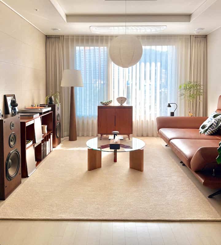 A warm brown and beige living room featuring a leather sofa and round glass coffee table with simple modern design