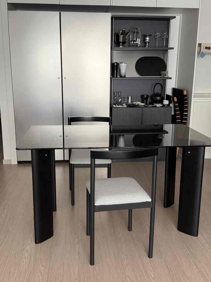 黒とナチュラルカラーが調和したキッチンスペース、ガラスのダイニングテーブルと椅子が整然と配置されたモダンなダイニングルーム