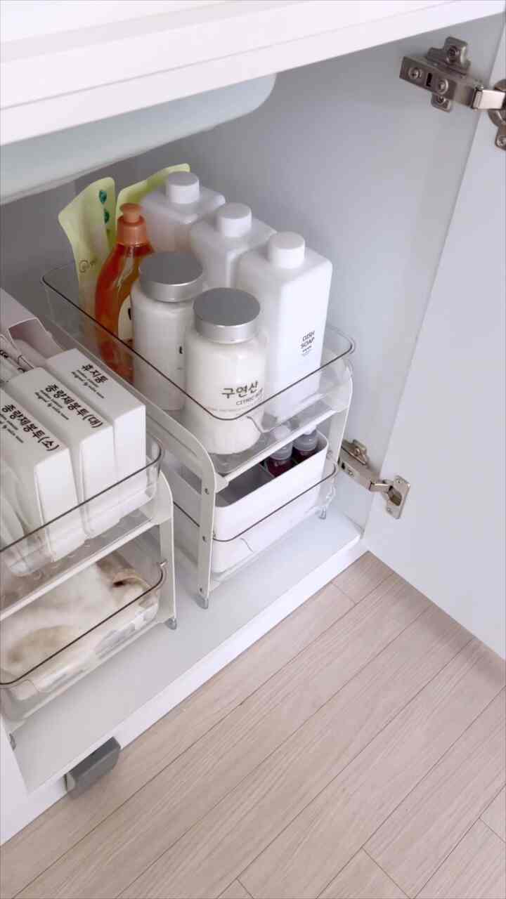 白を基調としたキッチン収納の内部、整理された容器と食器用洗剤が配置された雰囲気のあるインテリア