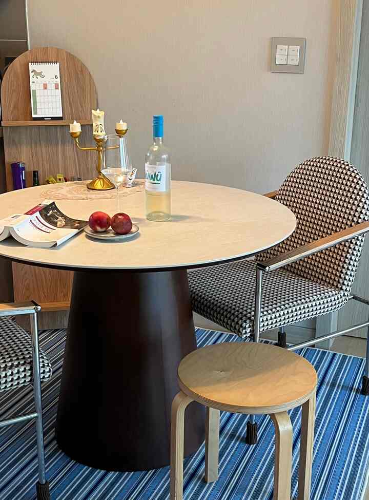 Blue and brown toned dining room featuring a round table with stools, wine bottle, and candle decor in a cozy setting