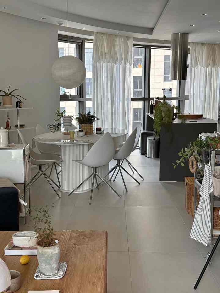白とグレーのトーンのダイニングルームとキッチン、木製テーブルと白いダイニングチェアが調和したモダンなインテリア