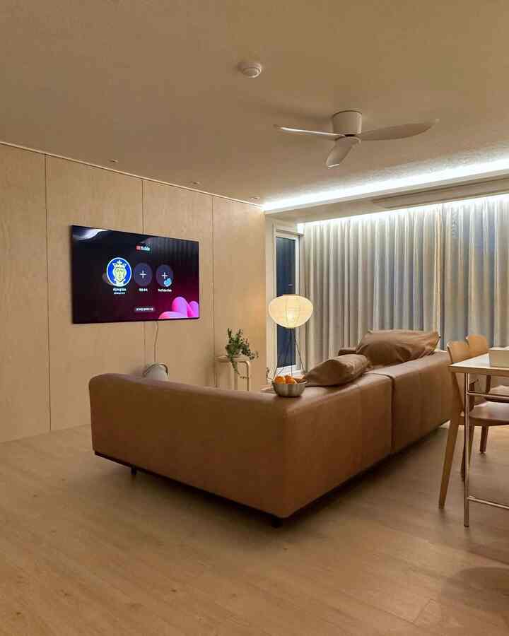 ブラウンのレザーソファとベージュの壁が配置されたモダンな二人暮らし向けのリビングとダイニングの空間