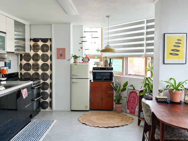 ホワイトとブラウンのトーンのキッチン、柱の隣にカラフルな冷蔵庫と収納が配置された自然な雰囲気のインテリア