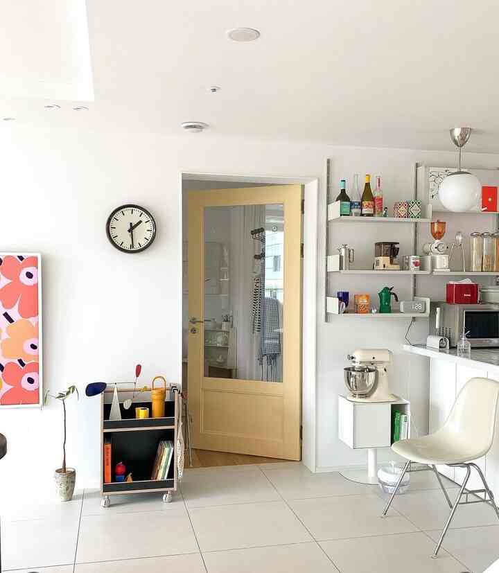 白と黄色のトーンの玄関スペース、キッチンワゴンとダイニングチェアが配置されたモダンで明るいインテリア