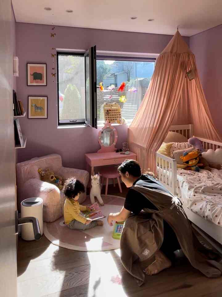 淡いピンクと白を基調とした子供部屋、子供用ベッドやピンクのドレッサー、ラグが配置された温かみのあるインテリア