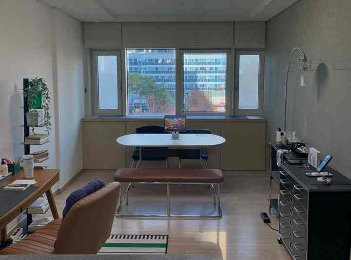 白と木目調が調和した二人暮らしのリビング、窓際ダイニングと作業スペースが配置されたミッドセンチュリーモダンなインテリア