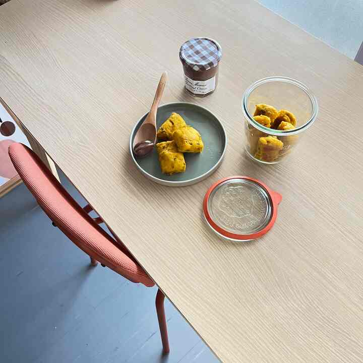 明るい木目調のダイニングテーブルとオレンジ色の椅子があるミニマルでナチュラルなホームカフェの空間