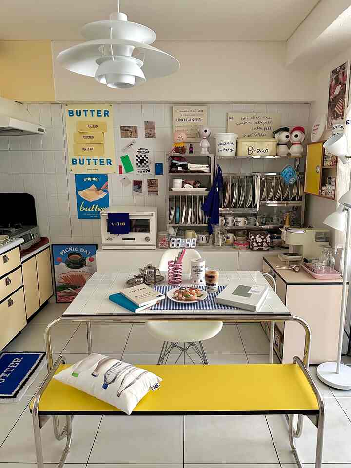 白と黄色のトーンのキッチン、収納キャビネットとダイニングテーブル、ベンチが配置された清潔感のある雰囲気のインテリア