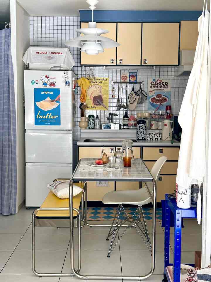 黄色と白を基調としたキッチン空間、タイルのダイニングテーブルと椅子、ペンダントライトが配置された雰囲気のあるキッチン