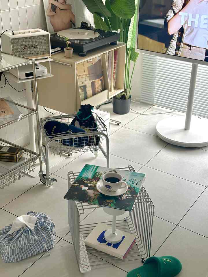 白い床とメタル家具が配置されたモダンリビング、ホームカフェの雰囲気と収納アイデアが特徴の空間