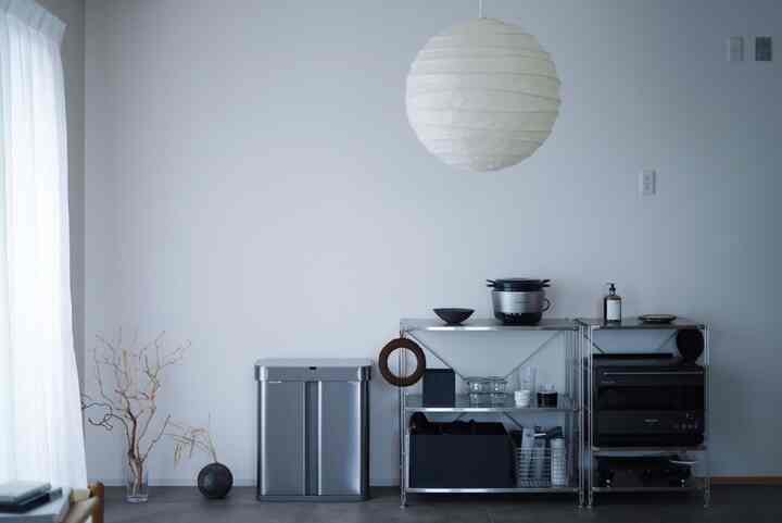 グレーとシルバーのトーンのキッチン空間、メタルシェルフとペンダントライトが配置されたシンプルなインテリア