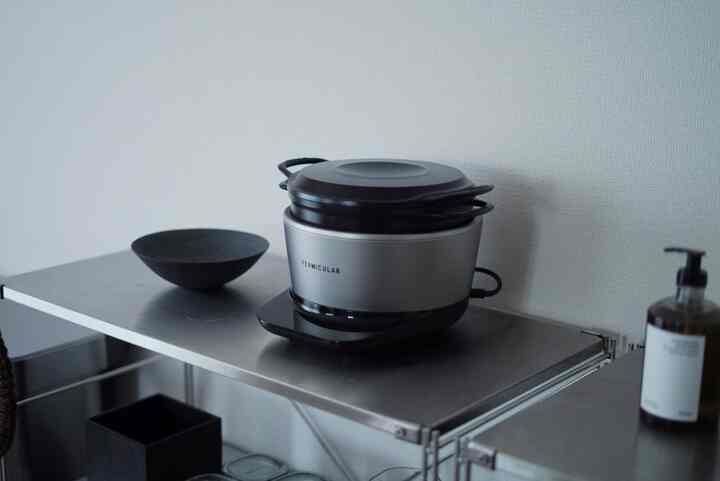 シルバーと黒を基調としたキッチン、ステンレス棚とバーミキュラの炊飯器が配置されたミニマルな雰囲気のインテリア