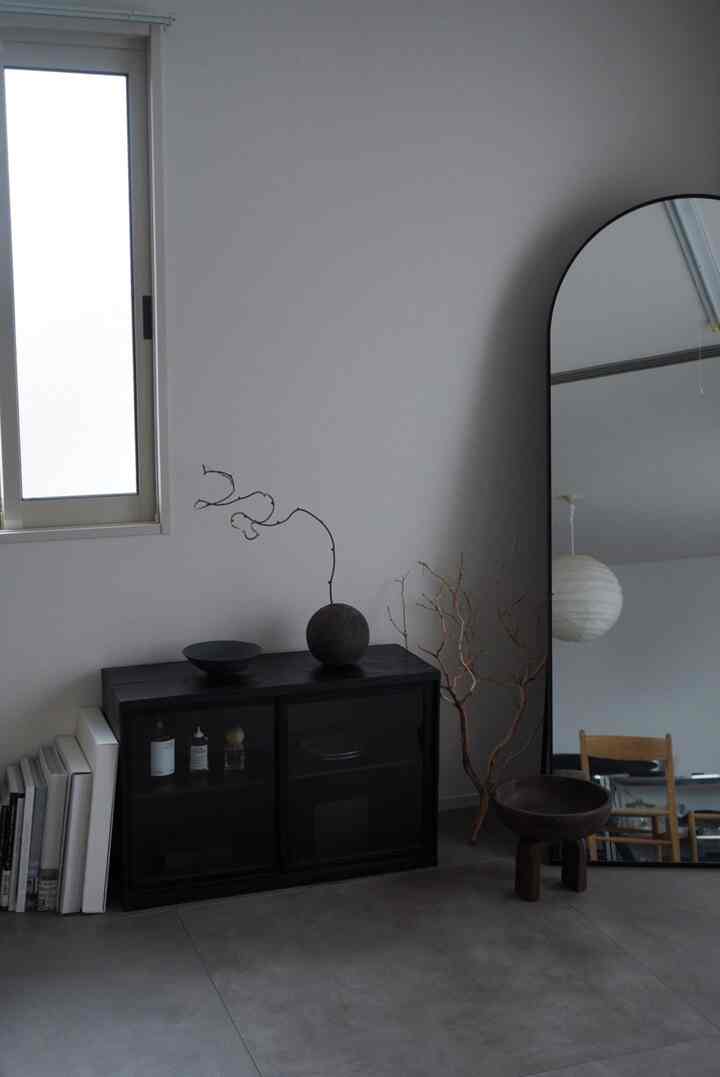 白い壁と黒いキャビネットが配置されたナチュラルでシンプルなリビング