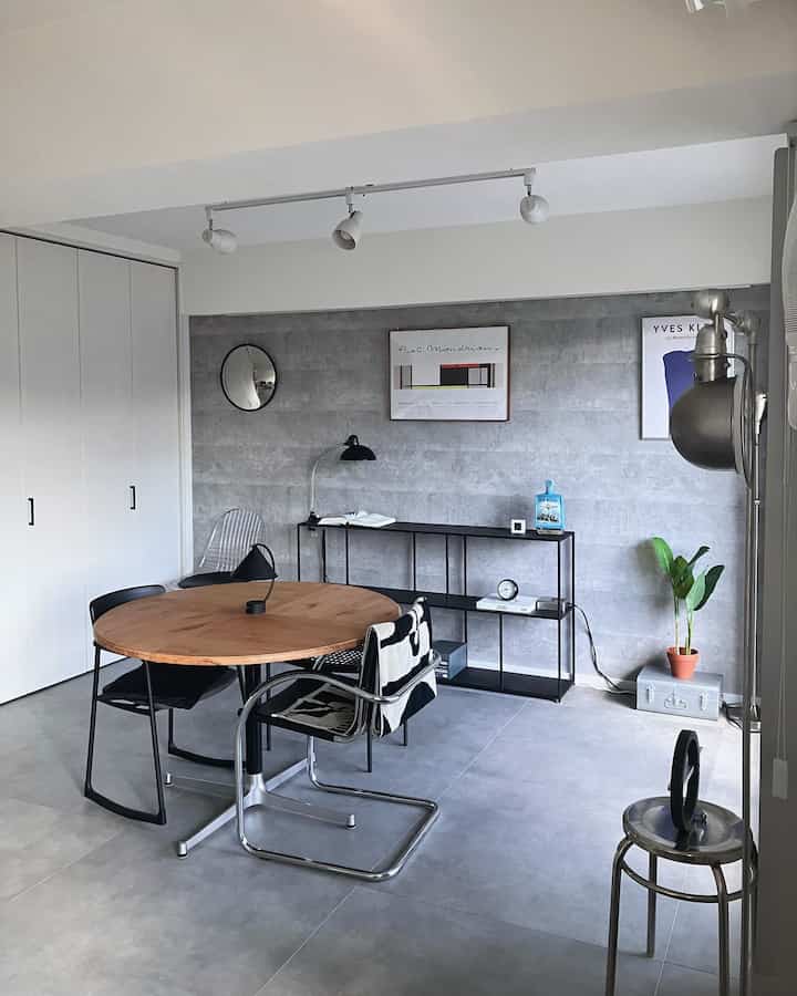 グレーの壁と床、木製のダイニングテーブルと黒い椅子が配置されたモダンでナチュラルなダイニングルーム