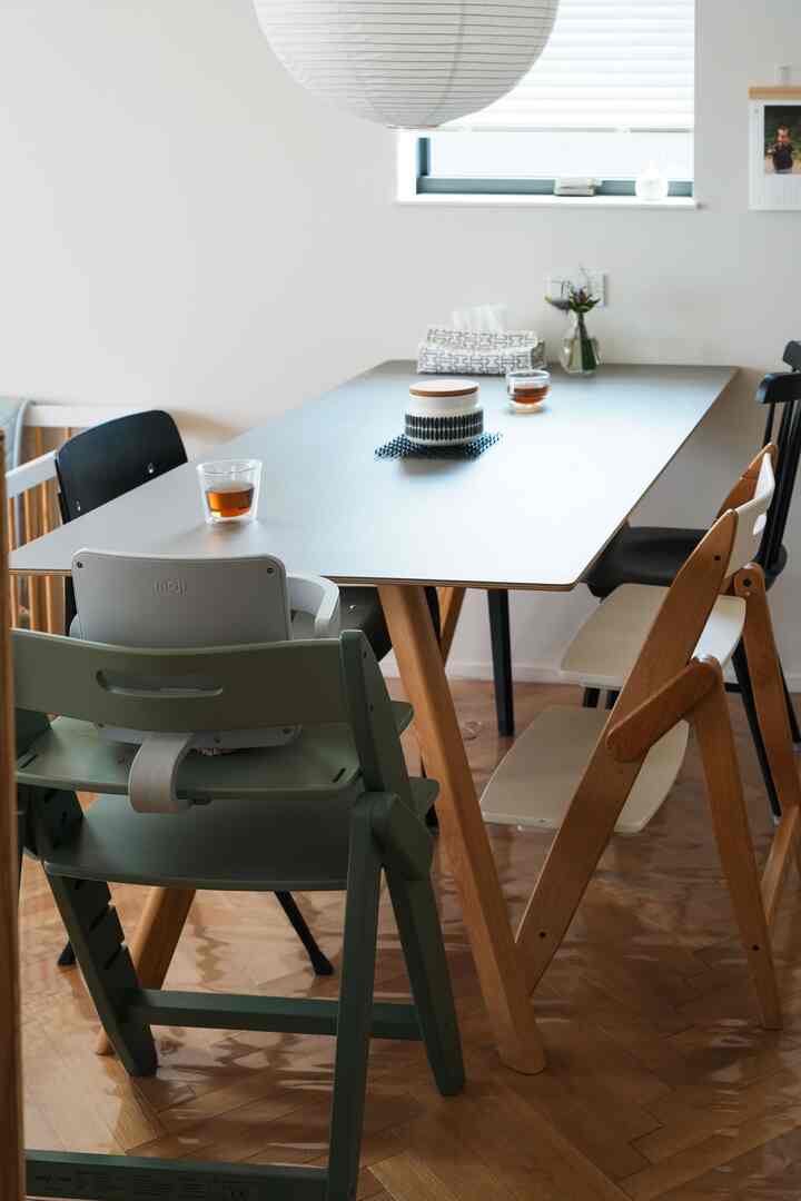 ナチュラルな木製床とグレーのダイニングテーブル、子供用椅子が配置された清潔でモダンなダイニングルームのインテリア