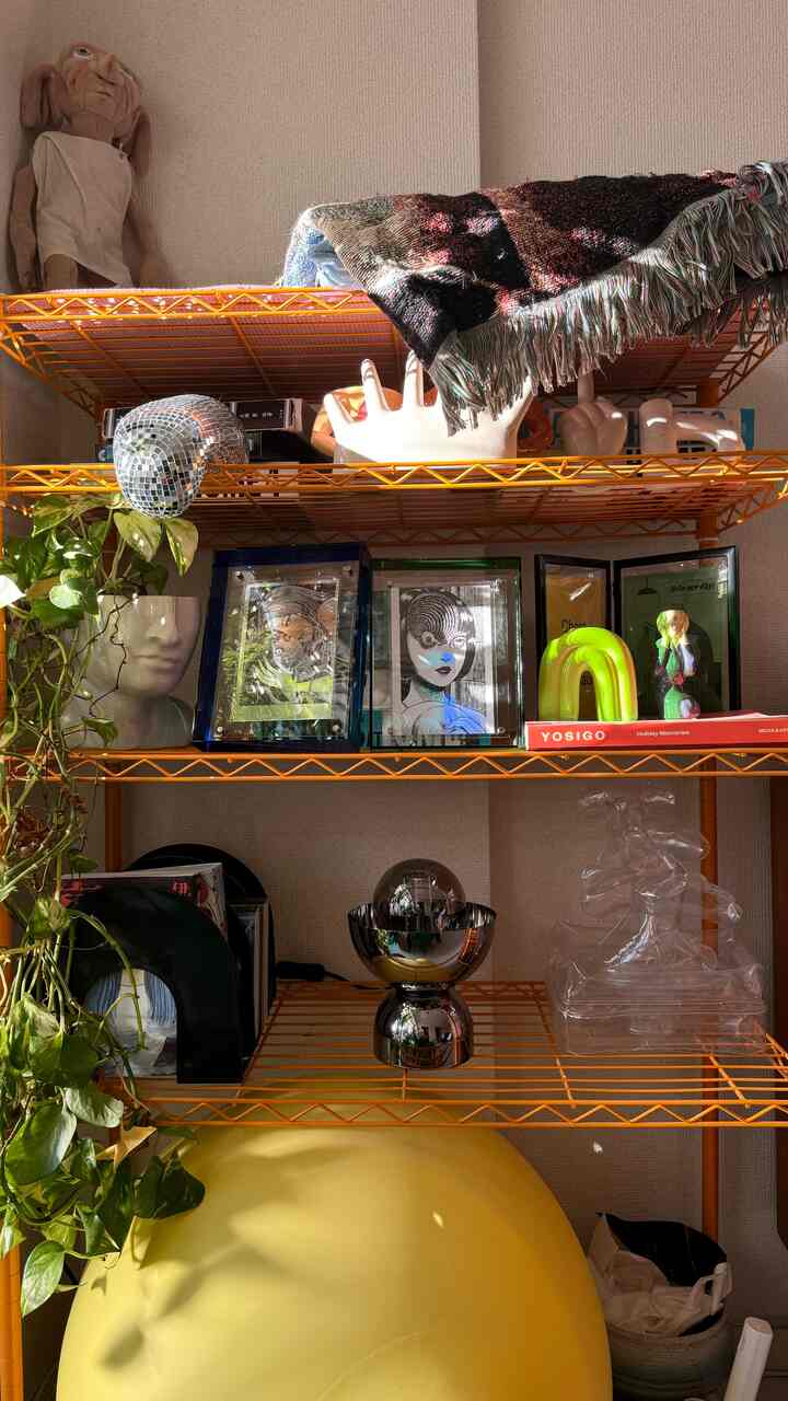 明るい黄色とオレンジの棚があるミニマルな空間、複数のアートオブジェと猫トイレを配置した雰囲気のあるインテリア