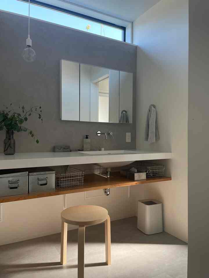 白と木目調のバスルーム、スツールとミニマルなデザイン要素が配置された清潔感のある空間