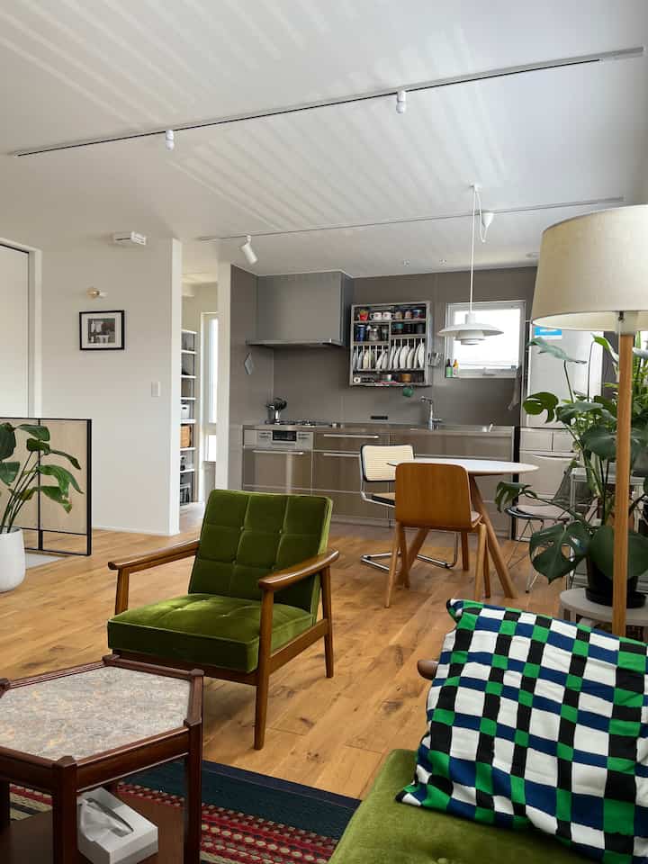 ナチュラルなウッドトーンとグリーンが調和した、モダンで落ち着いた雰囲気のダイニングとキッチンの空間