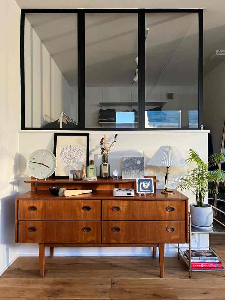 木目調の床とヴィンテージスタイルのサイドボードが並ぶ白い壁の背景の居心地の良いリビングスペース