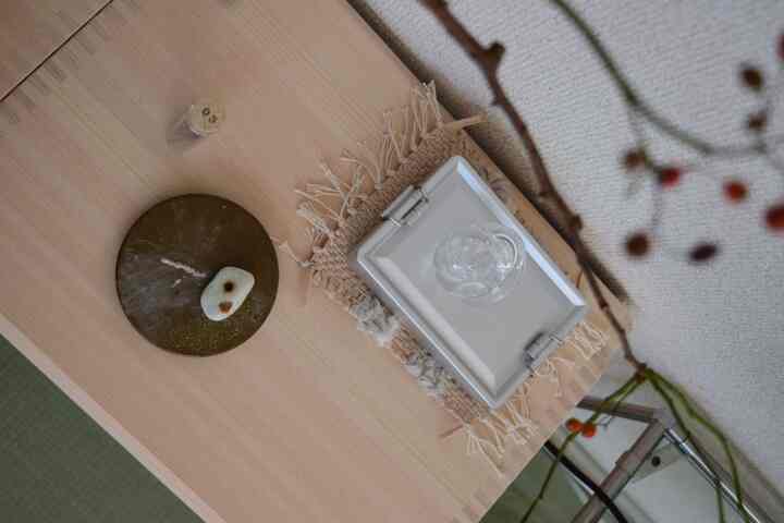 ナチュラルカラーのダイニングテーブルにマットとガラスのオブジェが配置されたシンプルなインテリア