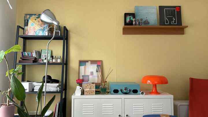 黄色い壁と白いキャビネット、黒の鉄製ラックが配置されたナチュラルトーンのディスプレイコーナー