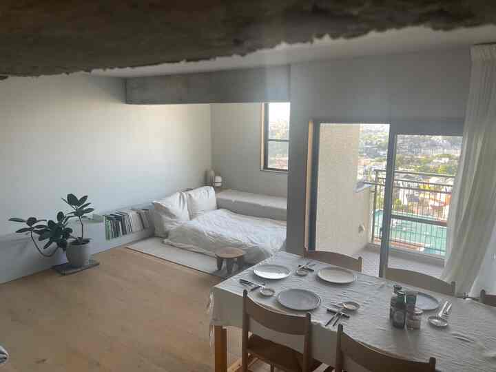 ホワイトとナチュラルウッドトーンのキッチンダイニング、カーテンとバルコニーが配置された雰囲気のある空間