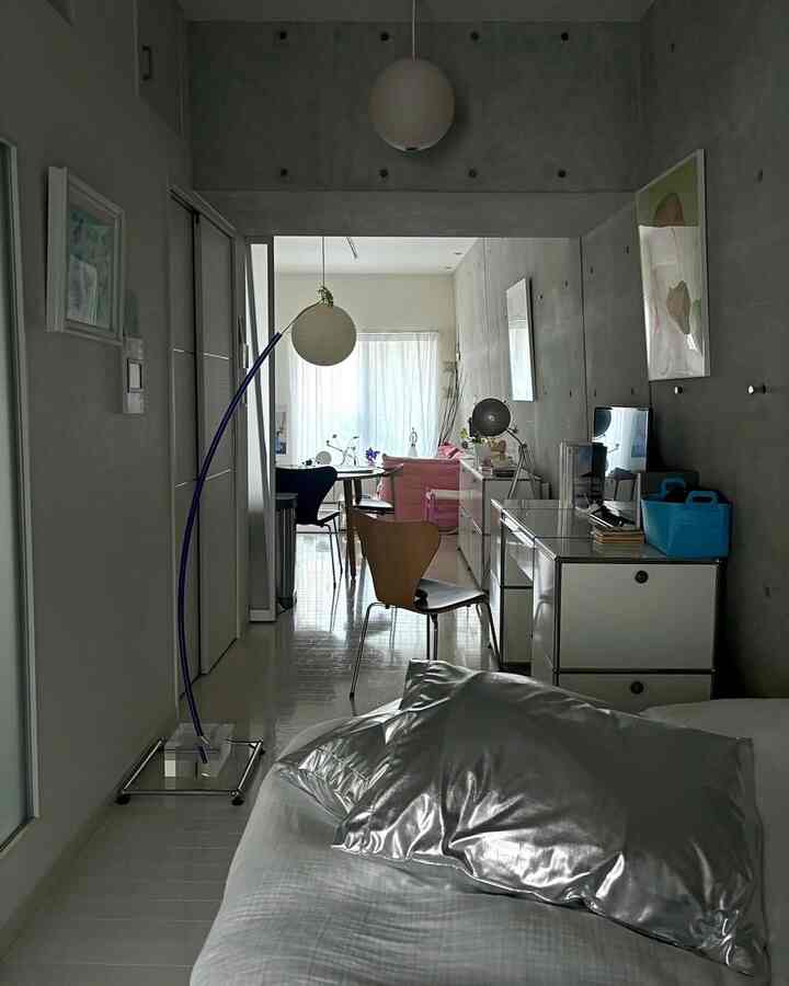 白とグレーのトーンのワンルーム、寝室とリビングが融合したシンプルモダンな空間にアカリのペンダントライトが配置されている