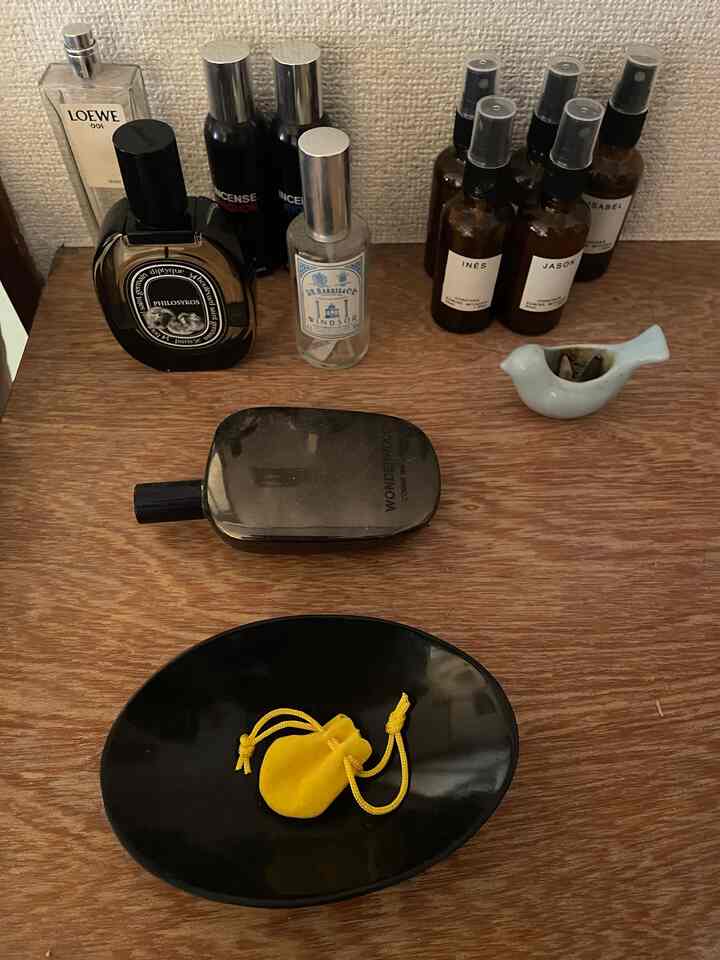 茶色の天板に香水瓶と黒いトレイが置かれた落ち着いた小物の空間