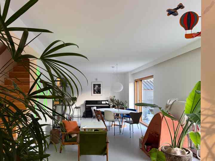 ナチュラルなグリーントーンのリビングダイニング、複数の椅子とテーブル、ペットハウスが置かれた雰囲気のあるインテリア