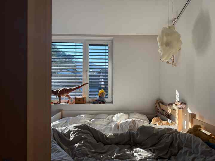 ホワイトと木目調のコンパクトな子供部屋、窓際におもちゃが並び、温かみのある雰囲気のインテリア