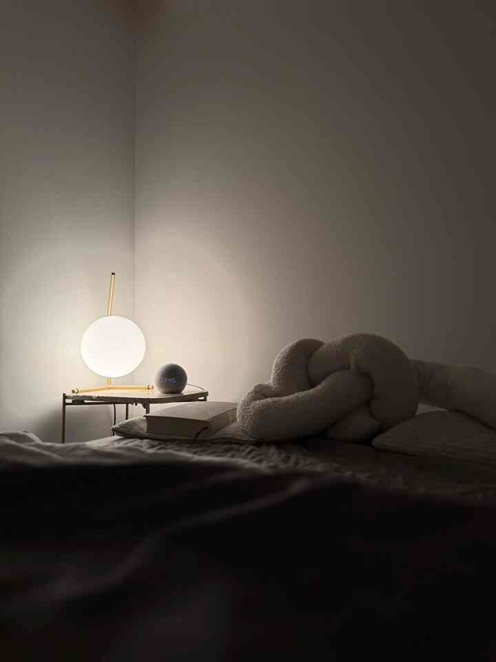 柔らかなホワイトとゴールドの照明がある落ち着いた寝室、ベッドサイドのテーブルランプが印象的な空間