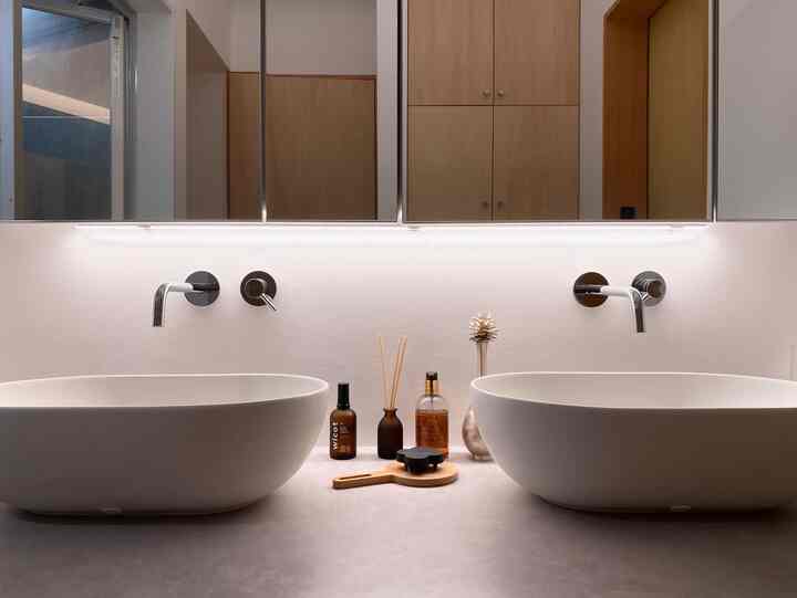 ナチュラルな木製キャビネットと白い洗面台が配置されたモダンなバスルーム