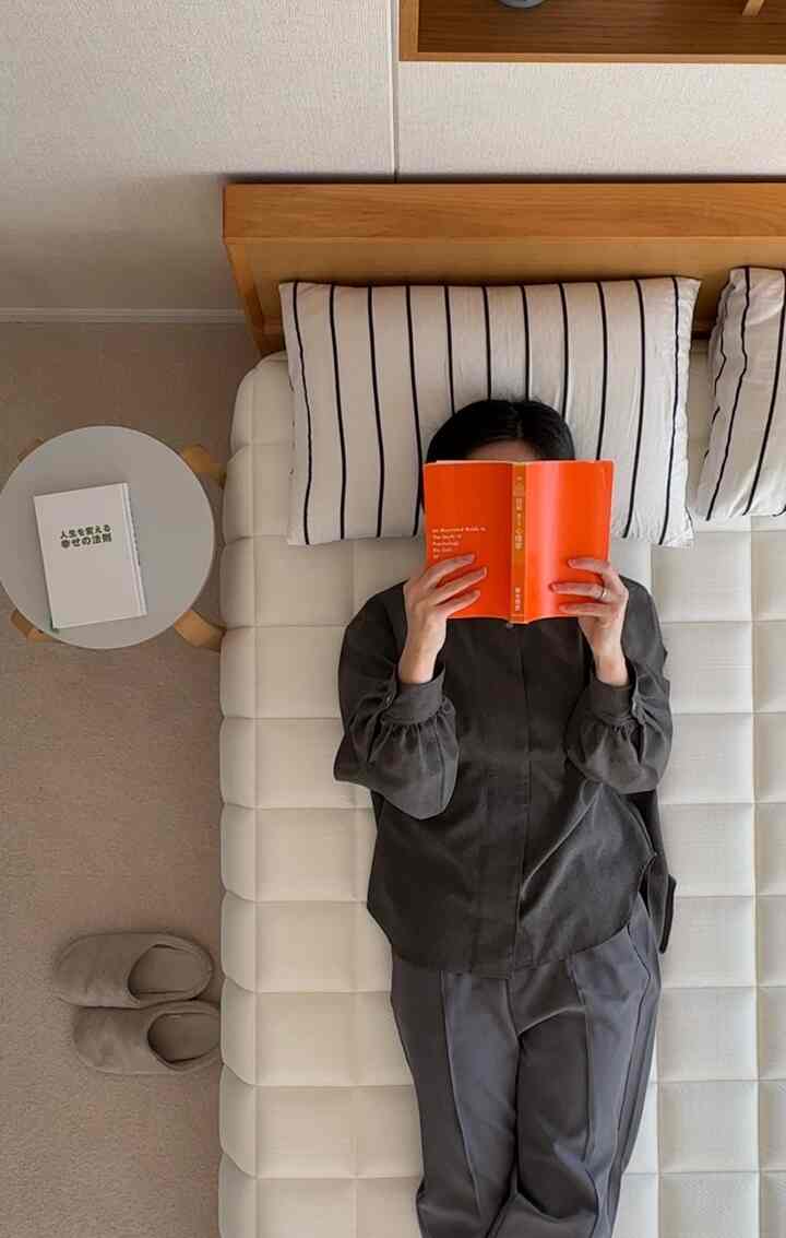 白と木目調が調和した6畳の寝室、シンプルなベッドと枕が配置された落ち着いた読書空間