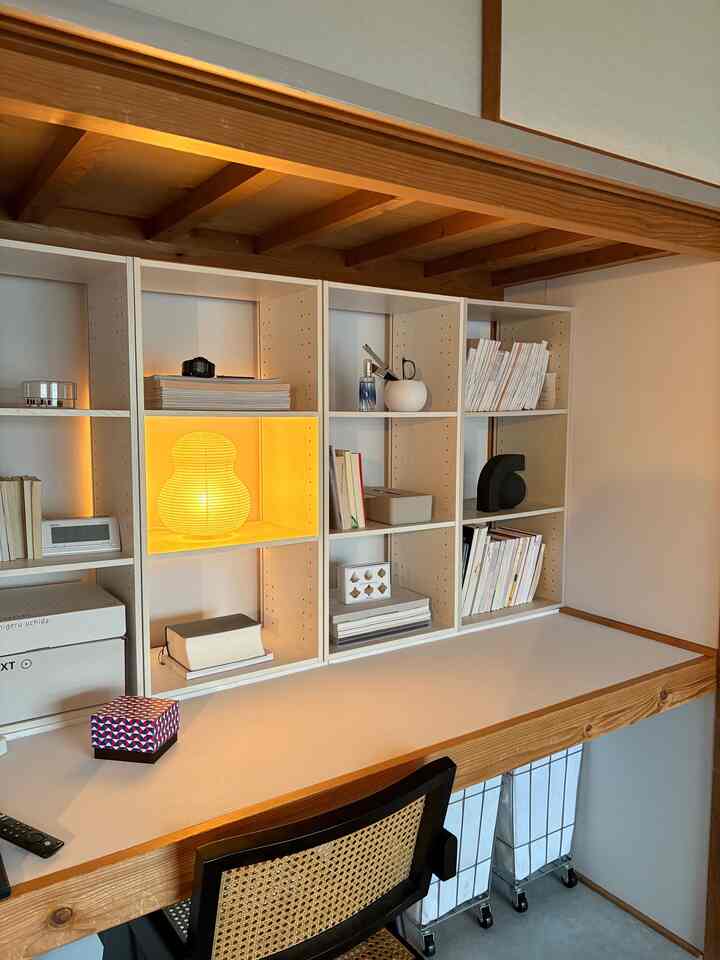 木目調の天井と白い収納棚が配置されたリビングのホームオフィス空間、デスクとオフィスチェアが印象的な雰囲気あるインテリア