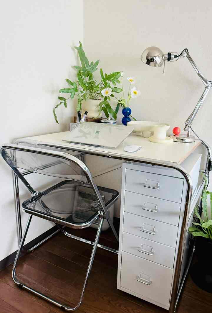 白とシルバーのトーンのホームオフィス、机とチェスト、透明な椅子が配置された雰囲気のあるインテリア