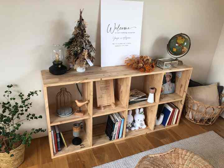 ナチュラルカラーの寝室、木製の棚に本やヴィンテージのオブジェが配置された雰囲気のあるインテリア