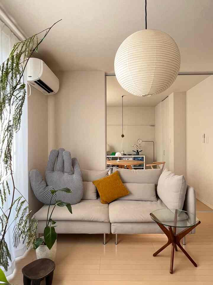 ナチュラルな色調のリビング、ベージュの3人掛けソファと木製サイドテーブルが配置されたシンプルで居心地の良い空間